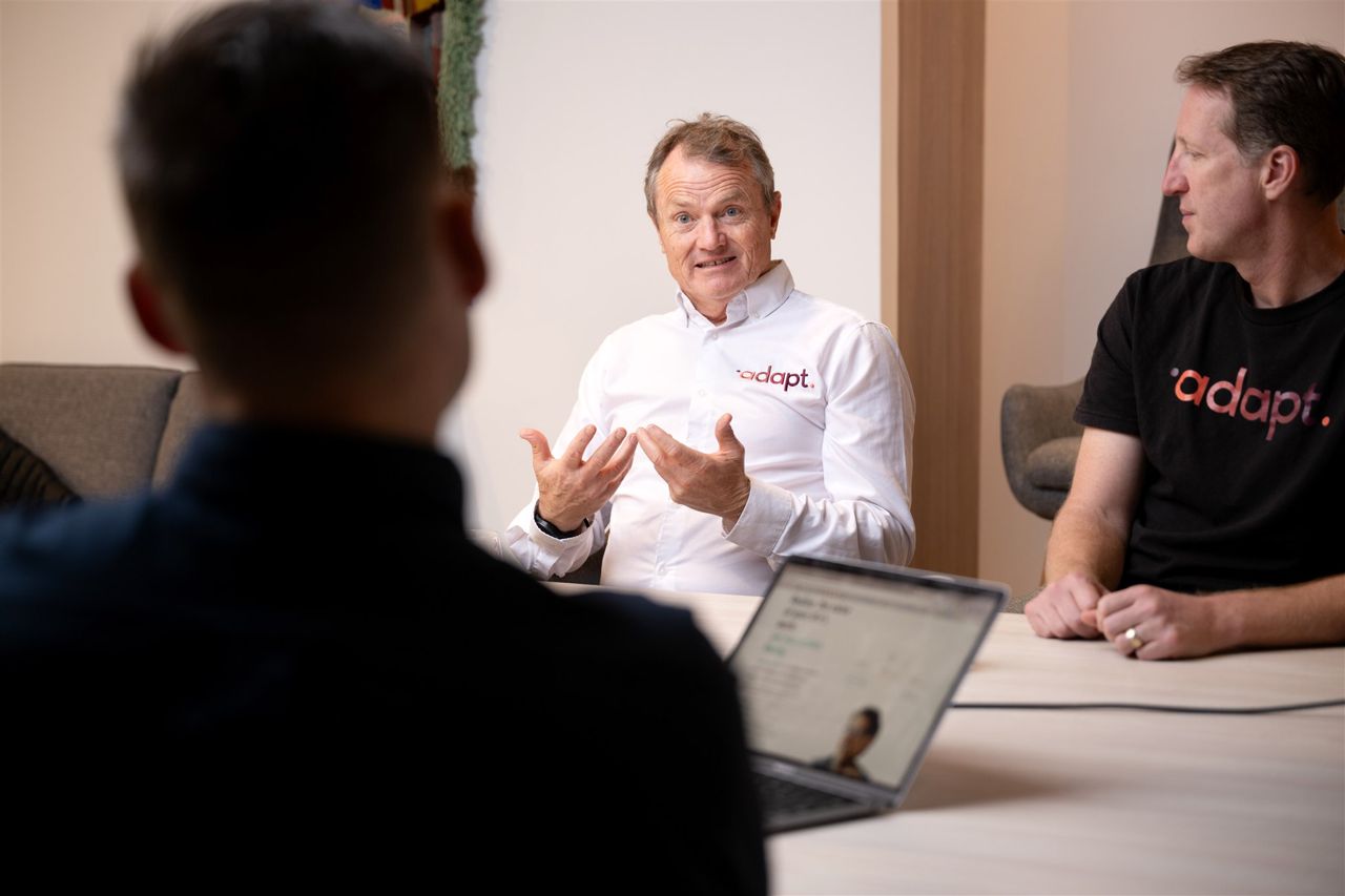 An Adapt coach working through the business with an owner, the platform open on the table.