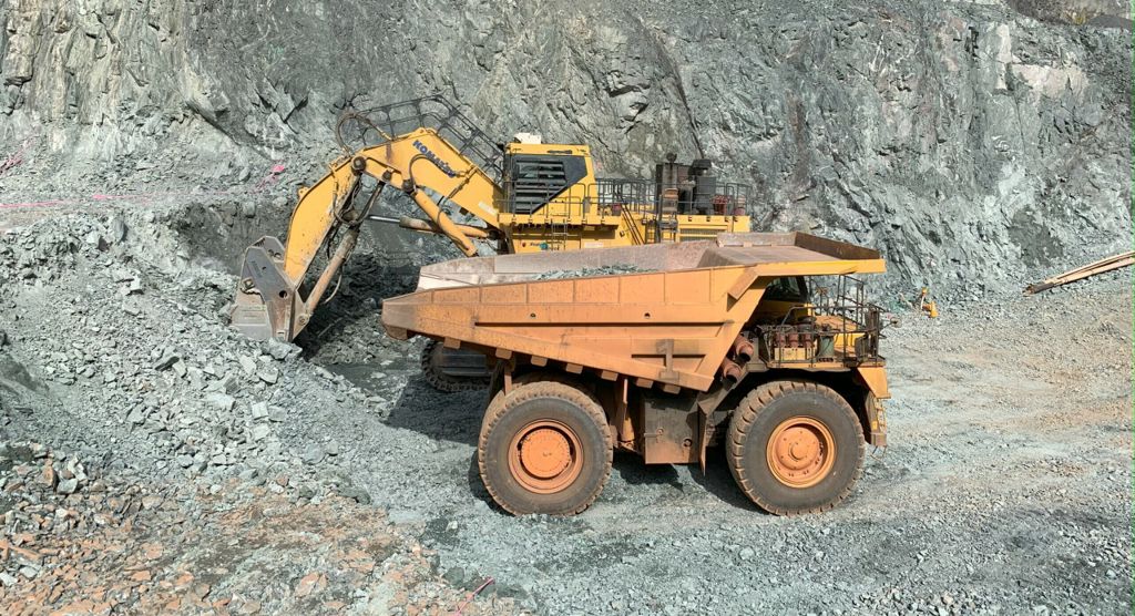 An excavator loading a haul truck in an open pit