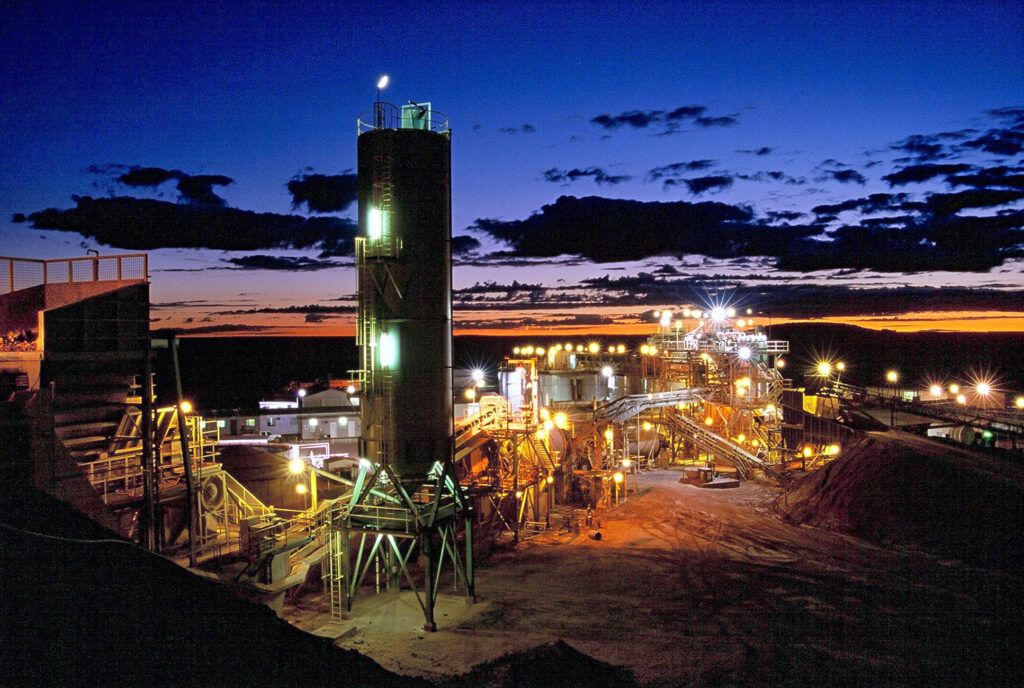 A lit mineral processing plant against a dusk sky
